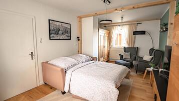 Ein Schlafzimmer mit Bett, Schreibtisch, Stuhl und einem Fenster mit Vorhängen.