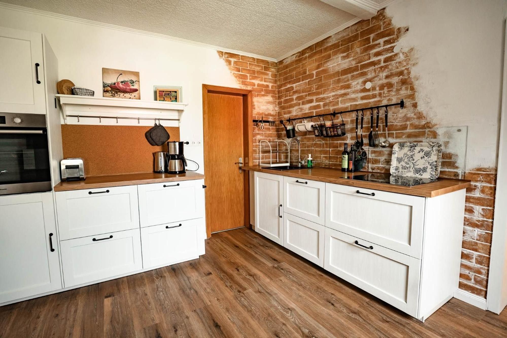 Eine Küche mit weißen Schränken, einer Backsteinwand und einer Holz Arbeitsplatte.