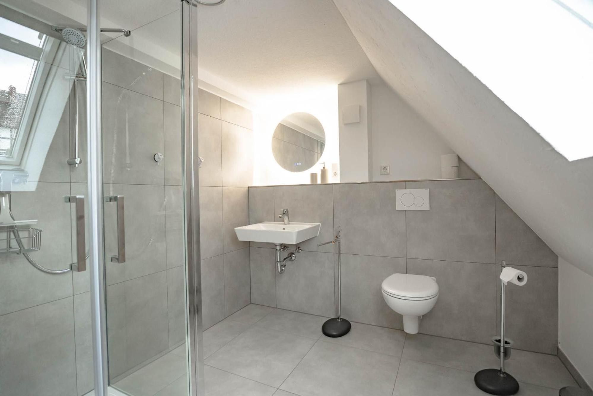 Ein modernes Badezimmer mit Duschkabine aus Glas, einem Waschbecken, einer Toilette und einem Bidet.