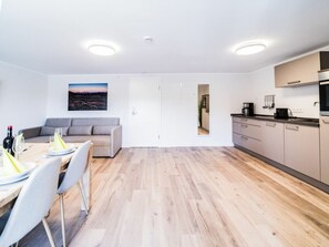 A modern apartment with a dining area, a sofa, a kitchen, and a view of the cityscape. - Holiday Apartment 706 (Winterberg)