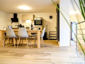 A modern kitchen with a dining area, wooden flooring, and a clock on the wall. - Holiday Apartment 706 (Winterberg)