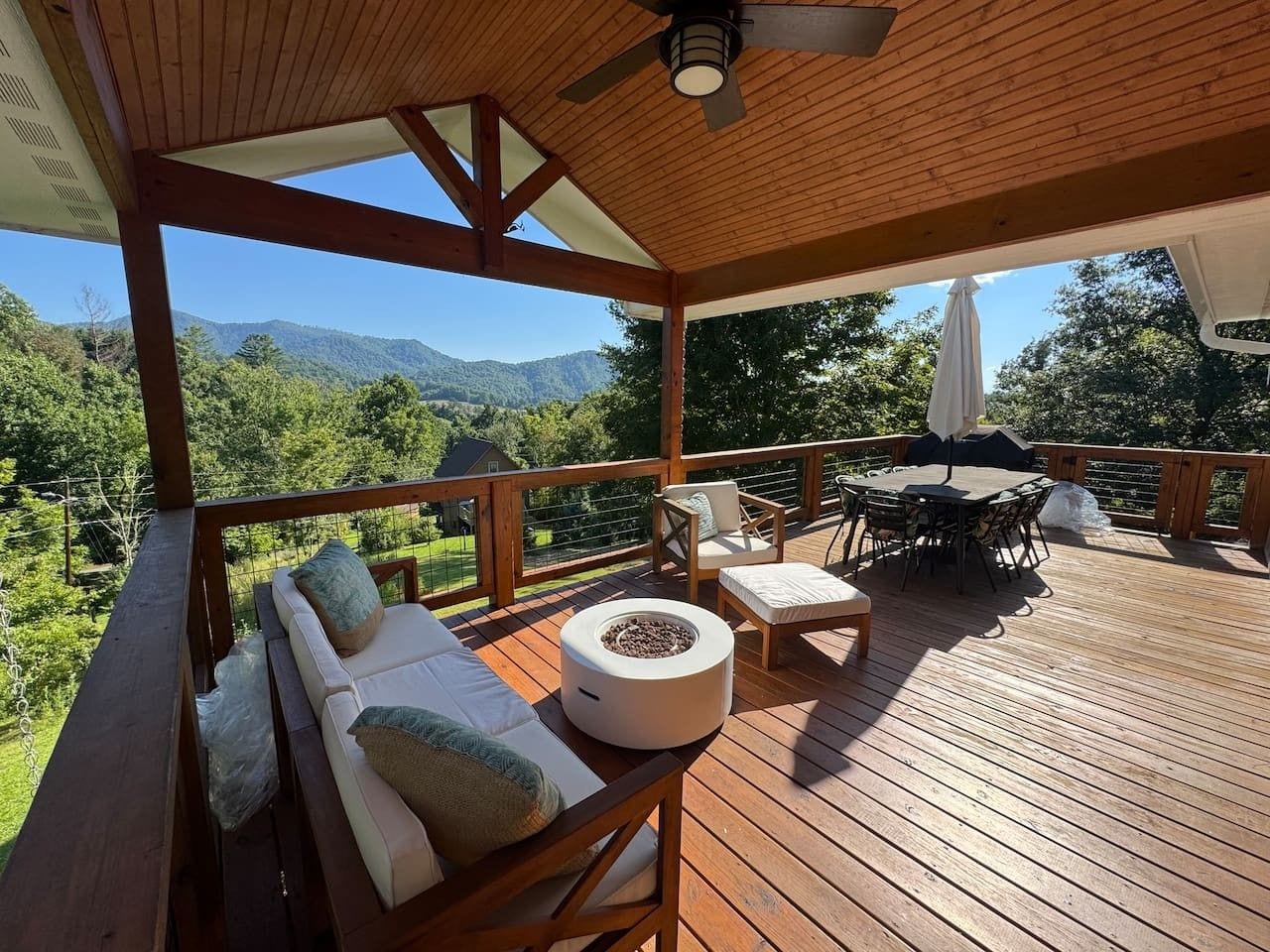 A wooden deck with outdoor furniture, including a sofa, chairs, and a table.
