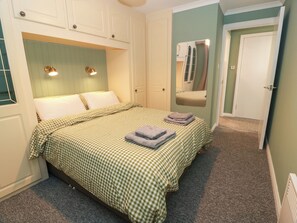 A bedroom with a bed, a mirror, and a door. - No.31 Craigard Road (Callander)