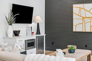 Eine moderne Küche mit Flachbildfernseher, Kühlschrank, Backofen und Essbereich mit Tisch und Stühlen.