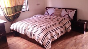Un dormitorio con cama, mesita de noche, cómoda y ventana con cortinas.