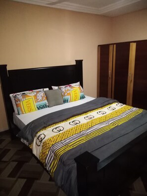 A bed with a black headboard, a patterned bedspread, and two pillows with a 'VERS' design.