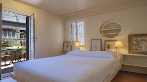 A bedroom with a bed, a window with decorative glass, a round mirror, and bedside lamps. - STUNNING DORSODURO HOME WITH SECRET GARDEN & TWO PRIVATE TERRACES (Venezia)