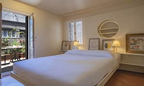 Une chambre à coucher avec un lit, une fenêtre ornée de vitraux, un miroir rond et des lampes de chevet.