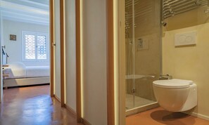 Une salle de bain moderne avec une douche à parois de verre, des toilettes et un porte-serviettes apparent.