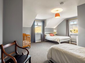 Ein Schlafzimmer mit Bett, Stuhl, Fenster und Deckenleuchte.