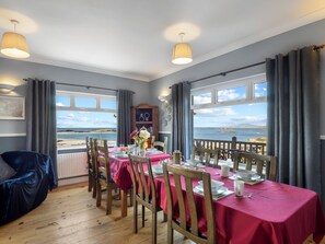 Un coin repas avec une table dressée pour six personnes, offrant une vue sur la côte.