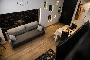 Moderni olohuone, jossa on tummanharmaa sohva, puulattia ja marmorilla päällystetty korosteseinä.