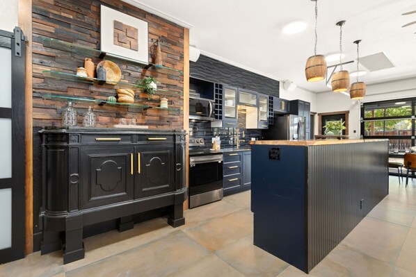 Una cocina moderna con armarios oscuros, una isla central y un diseño rústico en la pared.