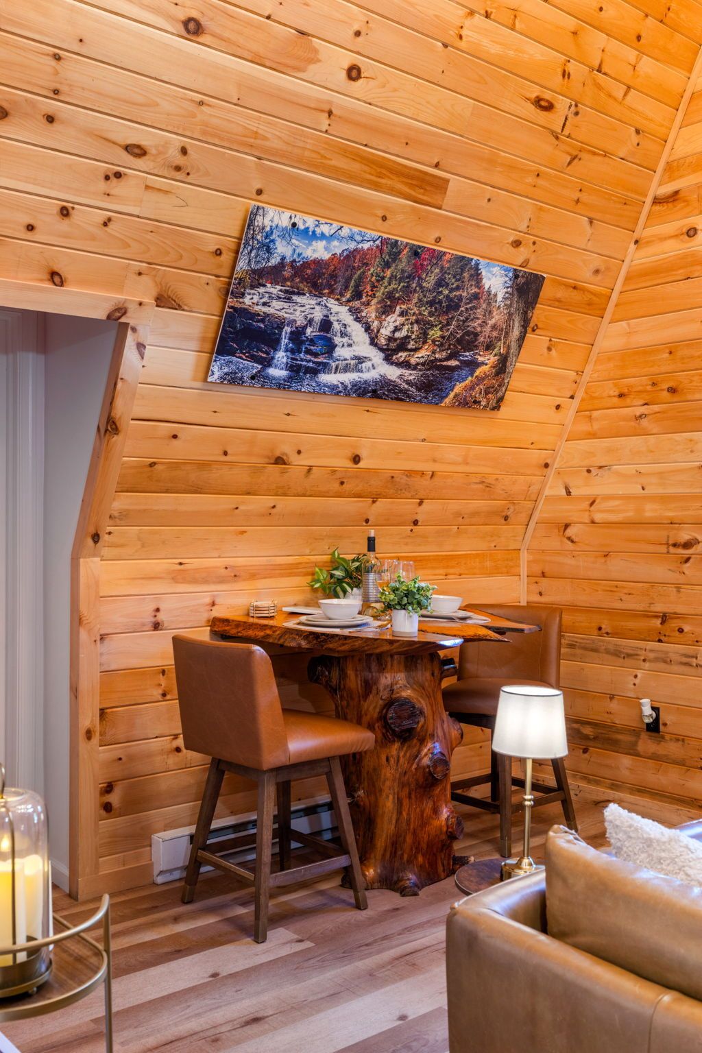 Un intérieur chaleureux, avec des éléments en bois, une table à manger dressée pour deux personnes, et des fauteuils en cuir disposés autour.