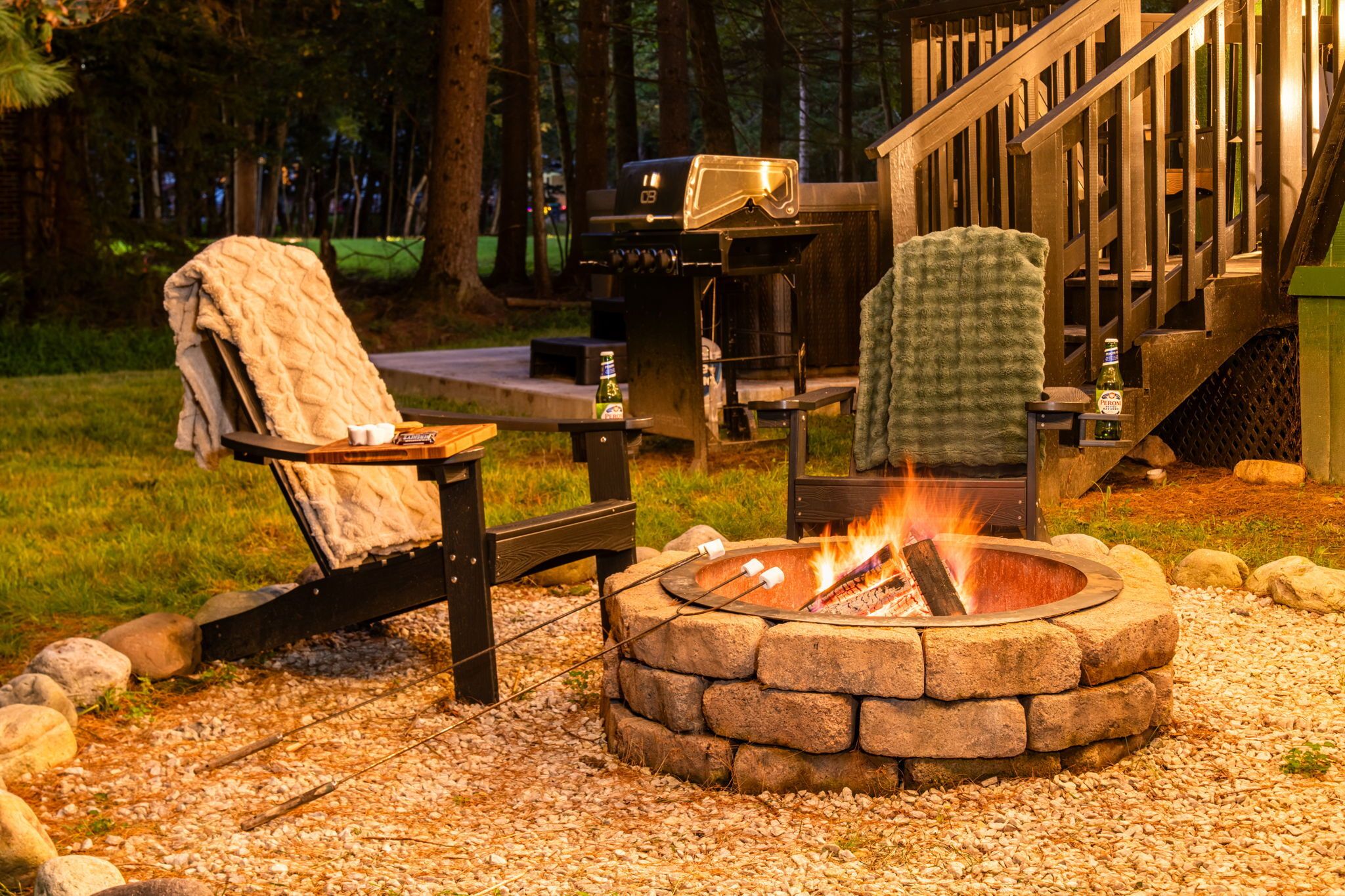 A fire pit with a chair and table, surrounded by a deck and trees.