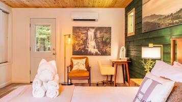 A cozy room with a bed, a chair, a desk, and a wall-mounted air conditioner.