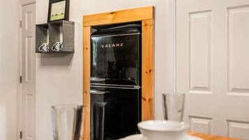 A modern kitchen with a black refrigerator, wooden frame, and a white door.