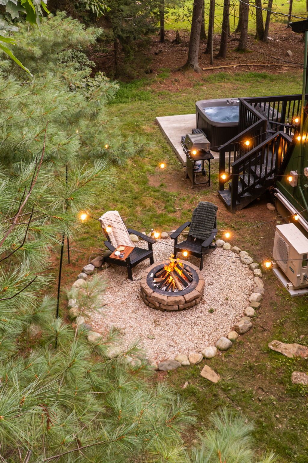 A backyard with a fire pit, outdoor seating, and a hot tub.