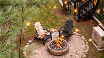 A backyard with a fire pit, outdoor seating, and a hot tub.