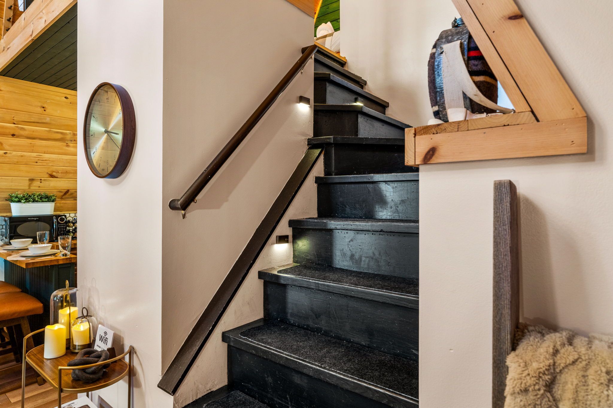 Una escalera con barandilla de madera y un reloj en la pared.