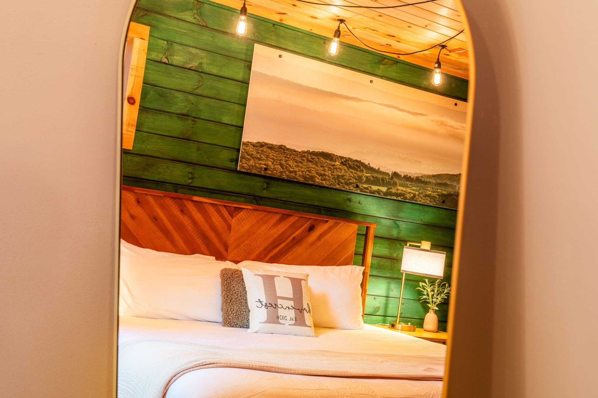 A bed with a wooden headboard, a nightstand with a lamp, and a wall-mounted picture.
