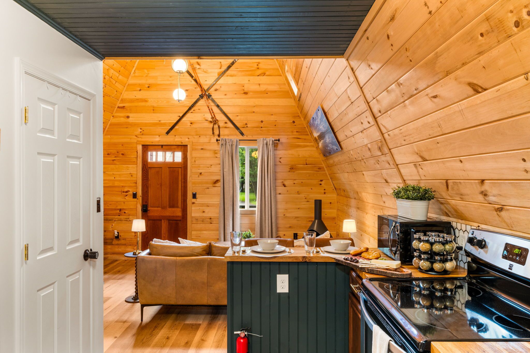 A cozy cabin interior with a wooden interior, a kitchenette, a dining area, and a living room.