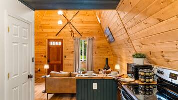 A cozy cabin interior with a wooden interior, a kitchenette, a dining area, and a living room.