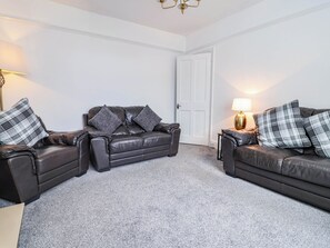 A room with two leather sofas, a white door, and a lamp on a side table. - 29 Brynford (Ellesmere Port)