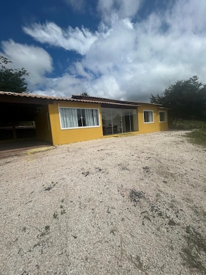 Un edificio amarillo con camino de grava y cielo despejado.