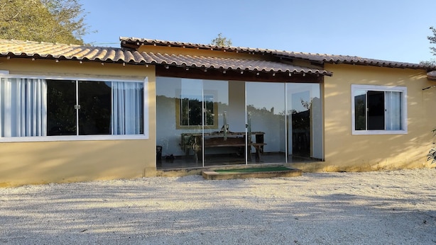 A single-story building with a tiled roof, a patio area with a table and chairs, and a gravel driveway. - Off Road House (Ibicoara)
