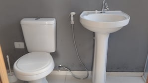 A bathroom with a toilet, a sink, and a shower head. - Off Road House (Ibicoara)