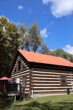 A log cabin with a red roof, a porch, and a window. - Cozy cabin with mini arcade games hot tub and fire pit (Logan)