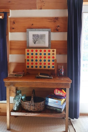 A wooden table with a pegboard, a framed picture, and a window with curtains. - Cozy cabin with mini arcade games hot tub and fire pit (Logan)