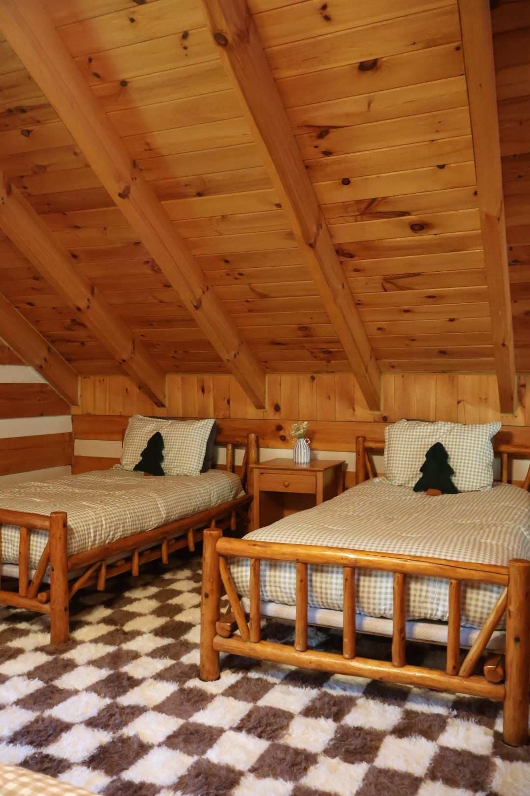 A cabin with two wooden beds, checkered bedding, and a checkered floor.