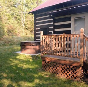 A cabin with a wooden deck and a hot tub. - Cozy cabin with mini arcade games hot tub and fire pit (Logan)