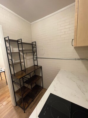 A kitchen with white brick walls, a wooden table with shelves, and a built-in oven.