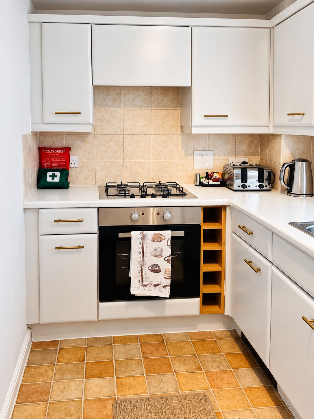 A kitchen with white cabinets, a gas stove, an oven, a toaster, and a kettle.
