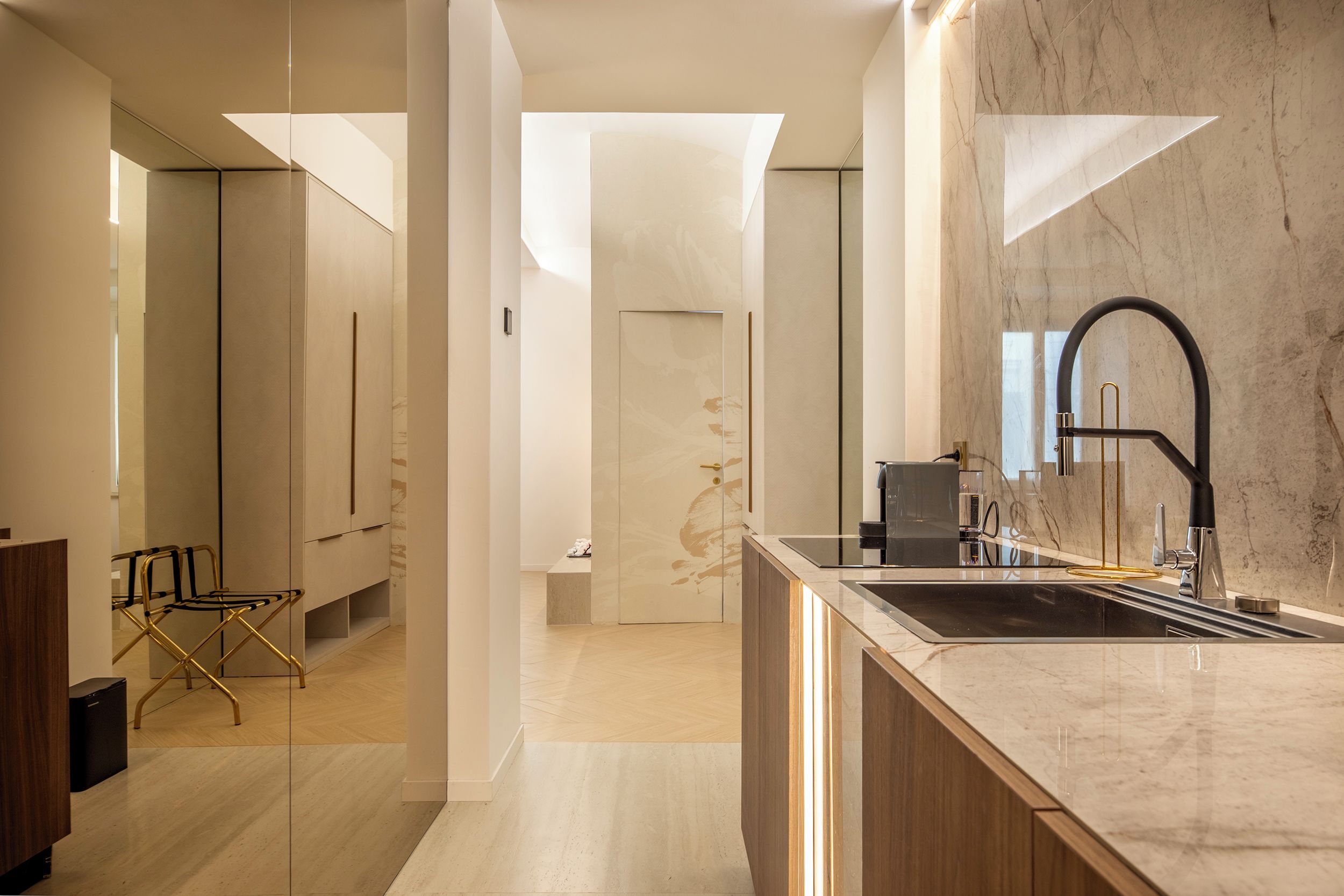 A modern kitchen with a marble countertop, a black faucet, and a built-in oven.