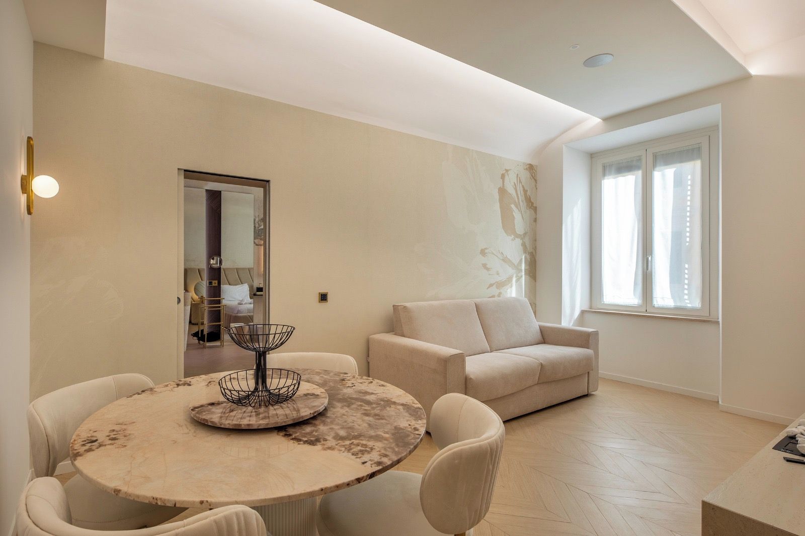 Un soggiorno moderno con un tavolo rotondo, un divano beige e una grande finestra.