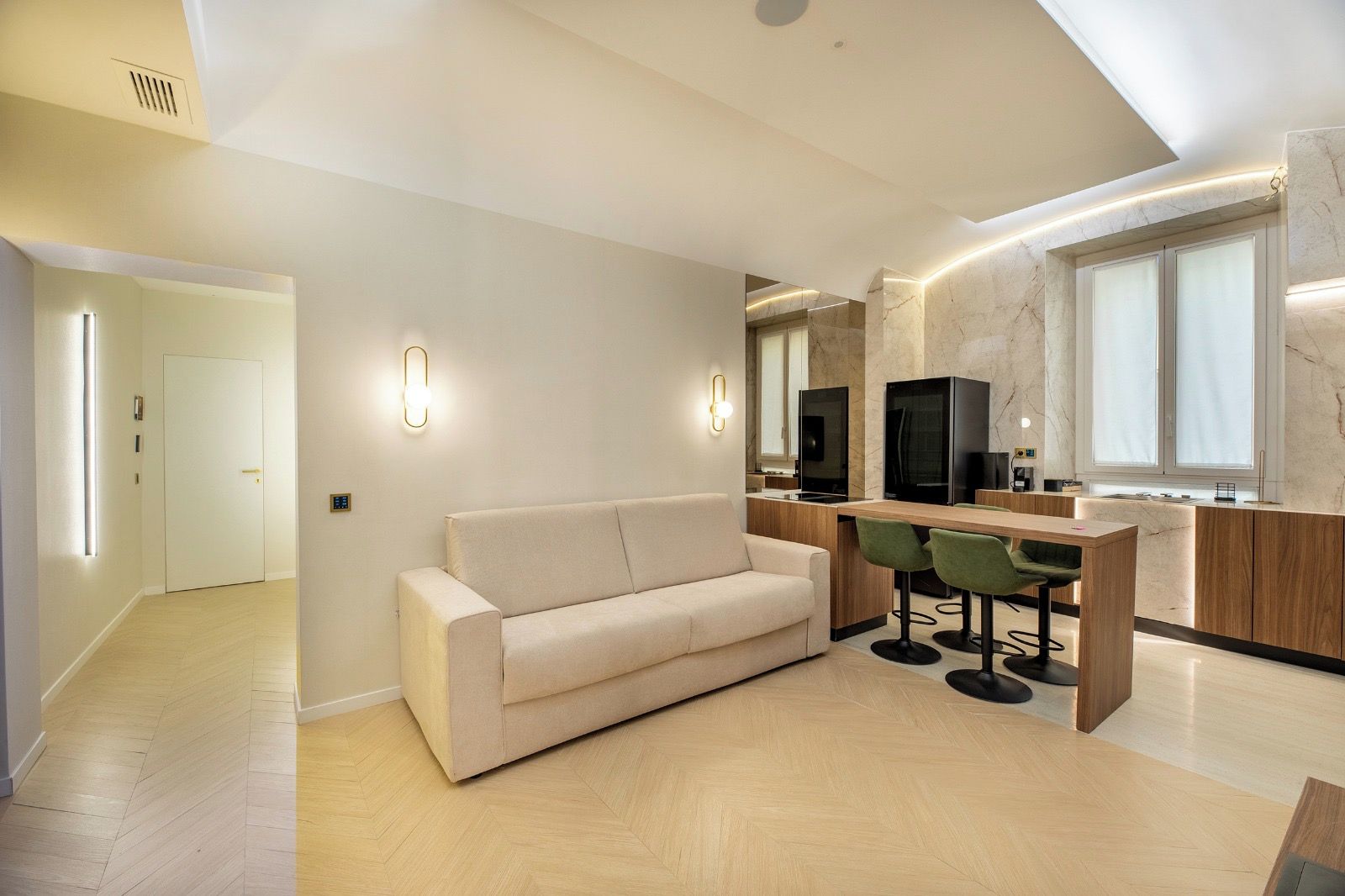 A modern living room with a sofa, a dining area with a bar, and a kitchen with marble countertops.