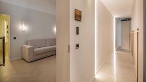Un interior moderno con un sofá, una lámpara de pared y una puerta con un cartel.