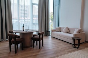 Ein modernes Wohnzimmer mit einem runden Holztisch, zwei Sofas und einem großen Fenster mit Vorhängen.
