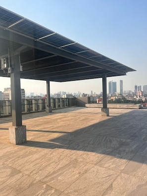 Eine Dachterrasse mit einer Solaranlage, blauem Himmel und Stadtansicht im Hintergrund.