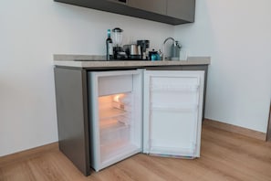 A compact kitchen with a built-in refrigerator, a coffee maker, and a kettle on the countertop. - Roma Residence | Luxury Suite 201 (Mexico City)
