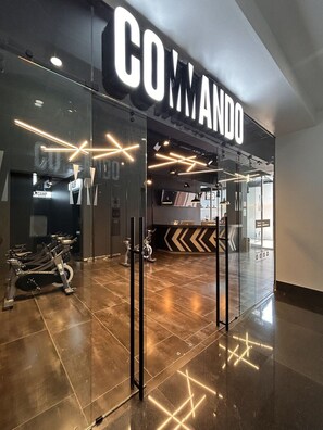 A gym entrance with a mirrored wall and exercise bikes. - Roma Residence | Luxury Suite 201 (Mexico City)