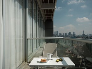 A balcony with a table, a chair, a plate with food, and a cup. - Condesa Residence - Roma Luxury Suite 307 (Ciudad de México)