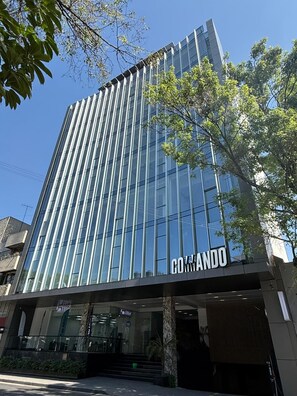 A modern building with a glass facade and the name 'COMANDO' prominently displayed. - Roma Residence | Luxury Suite 207 (Mexico City)