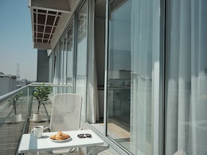 A balcony with a table, chair, and potted plants. - Condesa Residence - Roma Luxury Suite 505 (Mexico City)