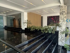 A modern lobby with a marble staircase, glass walls, and indoor plants. - Roma Residence | Luxury Suite 206 (Mexico City)