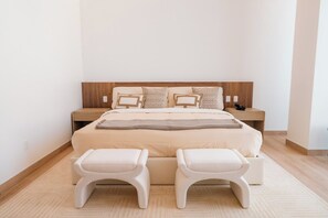 A modern bedroom with a large bed, two bedside tables, and two matching ottomans. - Condesa Residence - Roma Luxury Suite 602 (Mexico City)